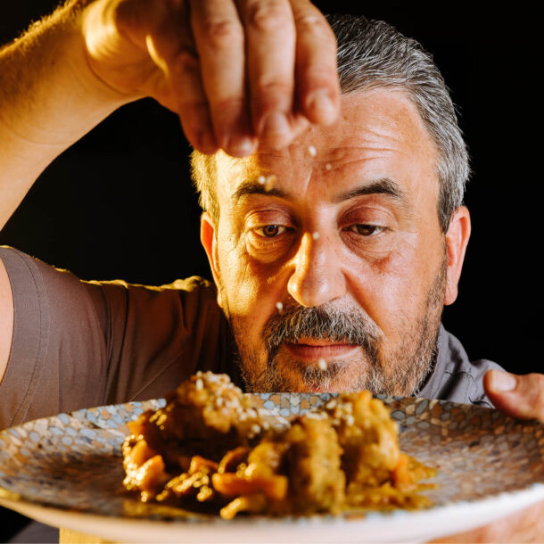 Lo chef Pepè cosparge di granella un piatto di carne in umido