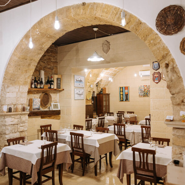 Sala della Trattoria Pugliese con arco in pietra e tavoli apparecchiati